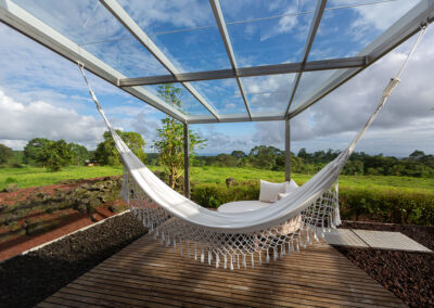 Villa Lechuza outside deck with hammock, green field and trees in the background